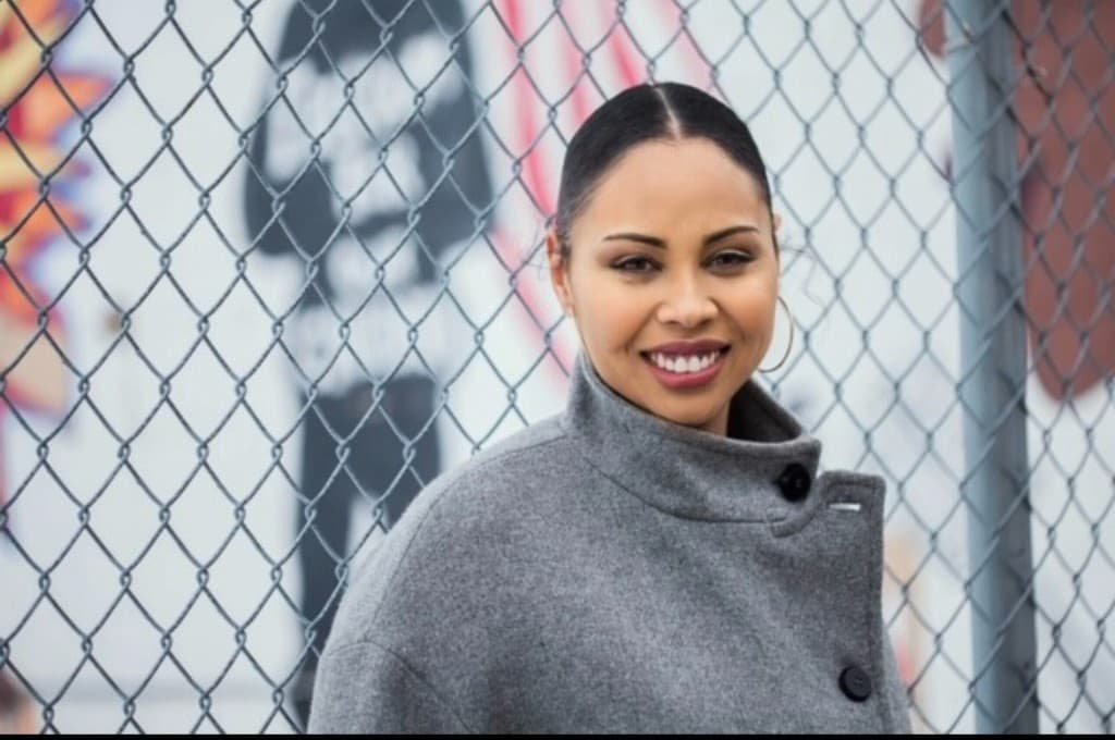 Colby Chapman in a gray coat by a chain-link fence